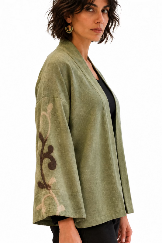 A woman wearing a cream merino wool cowl neck top with a cream grape design and patterned blue pants.