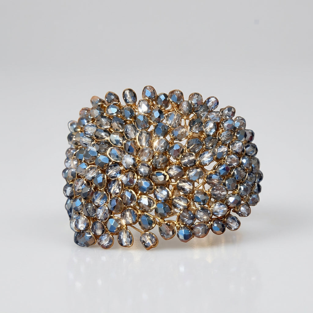 A wide cuff bracelet covered in faceted clear bohemian crystals set in gold-toned metal, worn on a person's wrist against a white background.