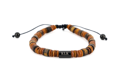 Men's bracelet with brown tiger's eye stone disc beads, black stainless steel centre bar engraved with KLK logo and adjustable cord fastening on white background