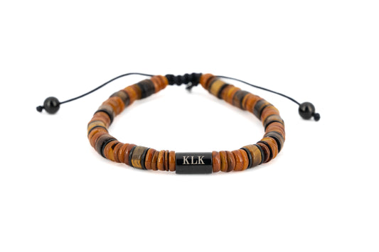 Men's bracelet with brown tiger's eye stone disc beads, black stainless steel centre bar engraved with KLK logo and adjustable cord fastening on white background