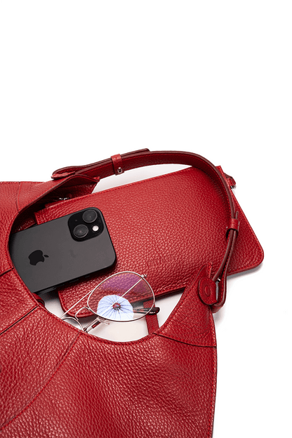 Red handbag with a black phone and eyeglasses on a white background