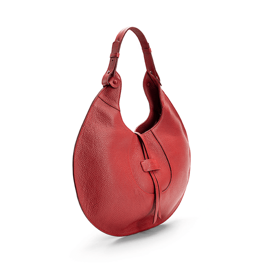 The side view of a red luxury designer pebble calf tote bag, showcasing the curved designer silhouette against a white background.