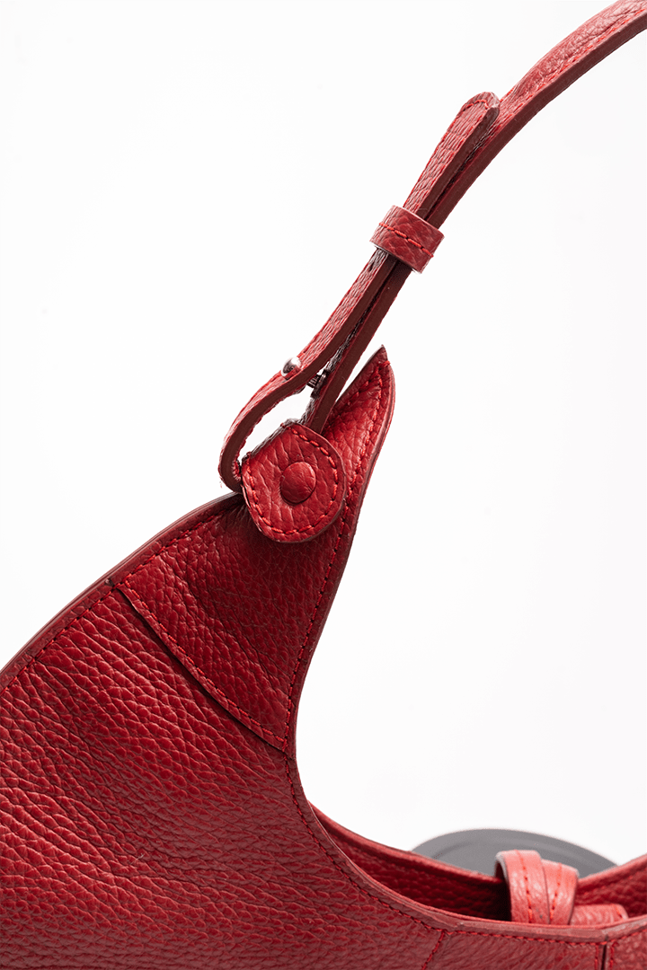 Close-up of a shoulder strap on a designer luxury red pebble calf tote bag.