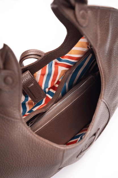Inside view of the colourful lining of a brown pebble calf tote bag on a white background.