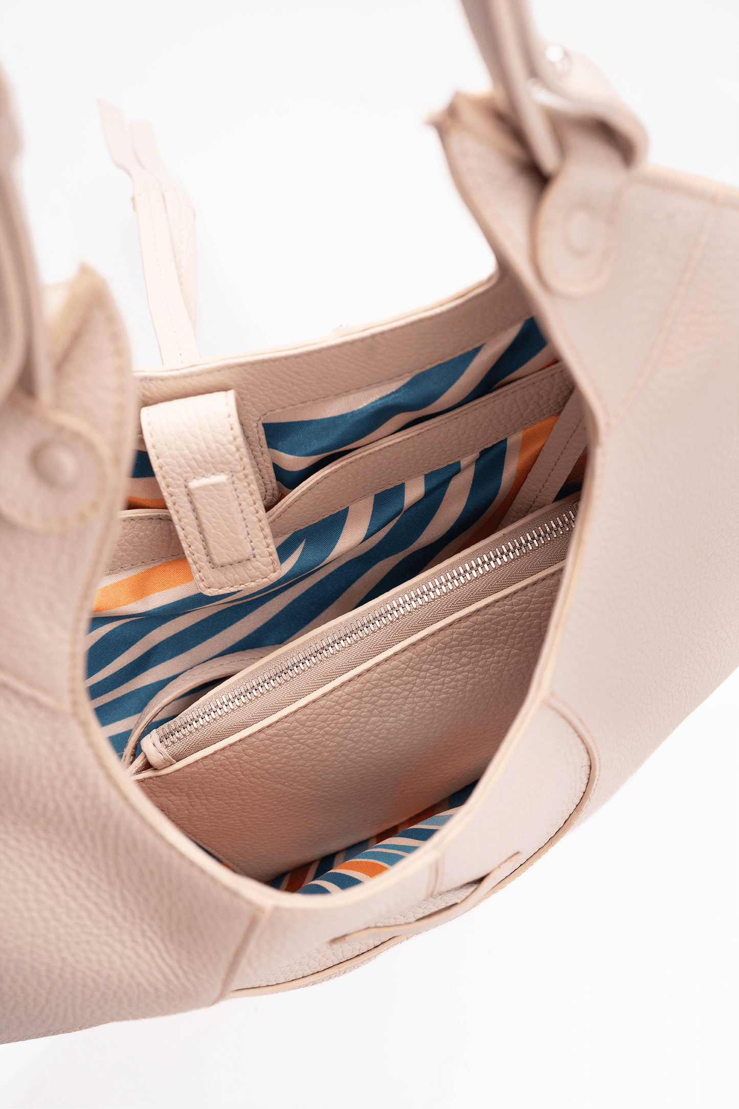 Inside view of the colourful lining of a beige pebble calf tote bag on a white background