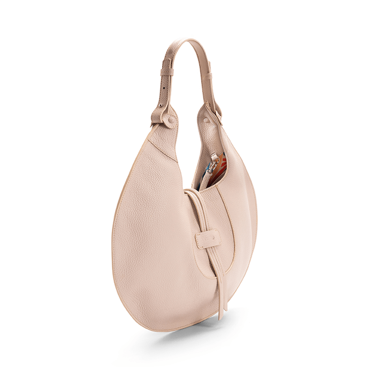 The side view of a beige luxury designer pebble calf tote bag, showcasing the curved designer silhouette against a white background.