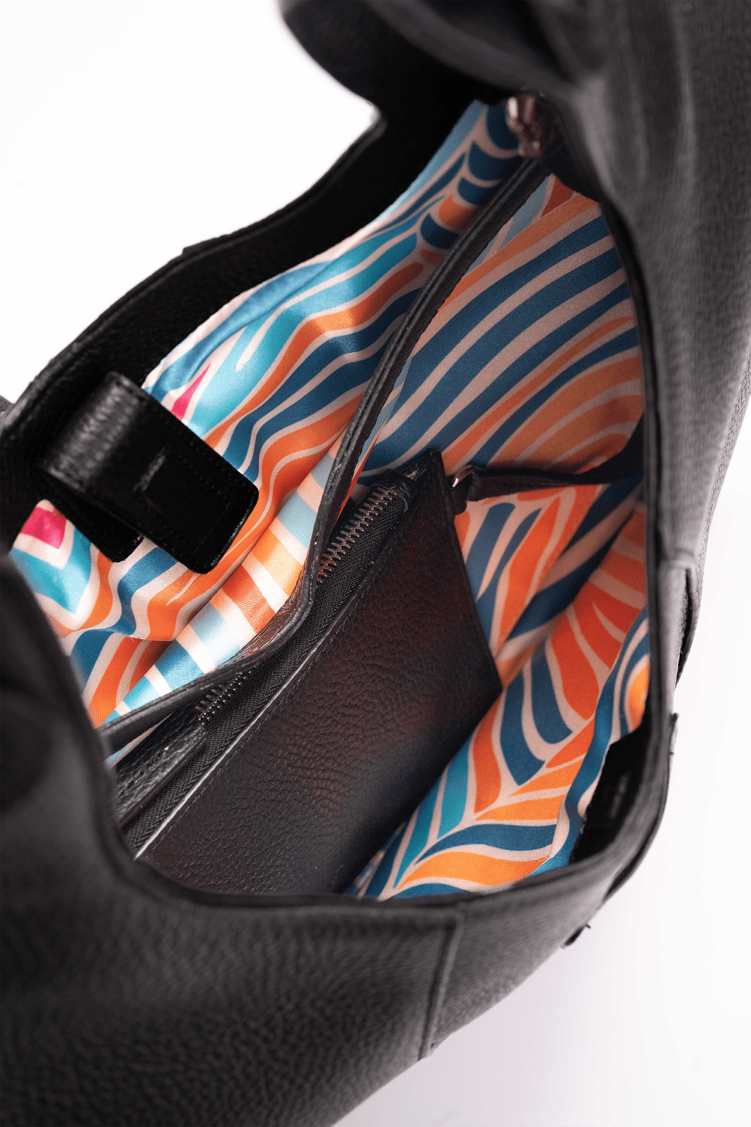 Inside view of the colourful lining of a black pebble calf tote bag on a white background.