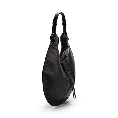 The side view of a black luxury designer pebble calf tote bag, showcasing the curved designer silhouette against a white background.