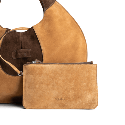 Close-up front view of a caramel and chocolate luxury suede tote bag with a matching small pouch attached by a strap, displayed on a white background.