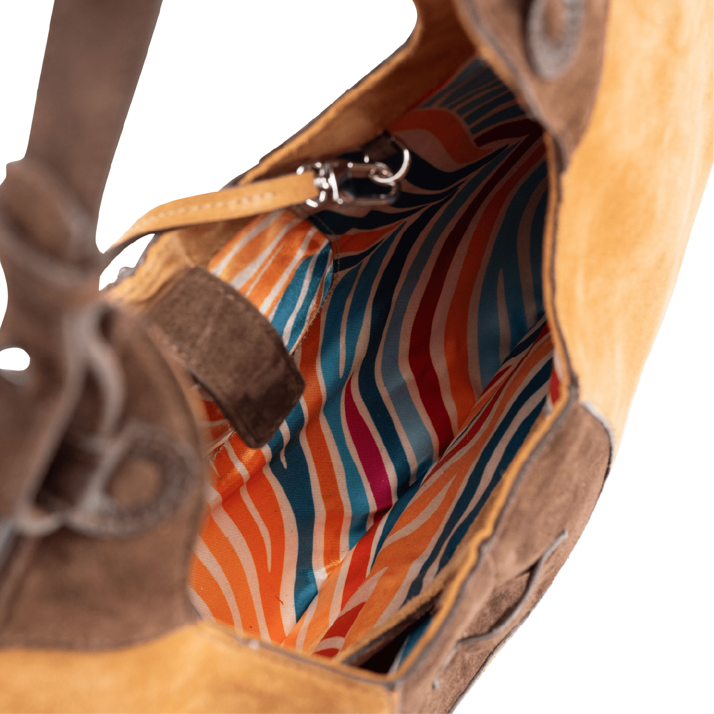 Inside view of the colourful lining of a caramel suede tote bag on a white background
