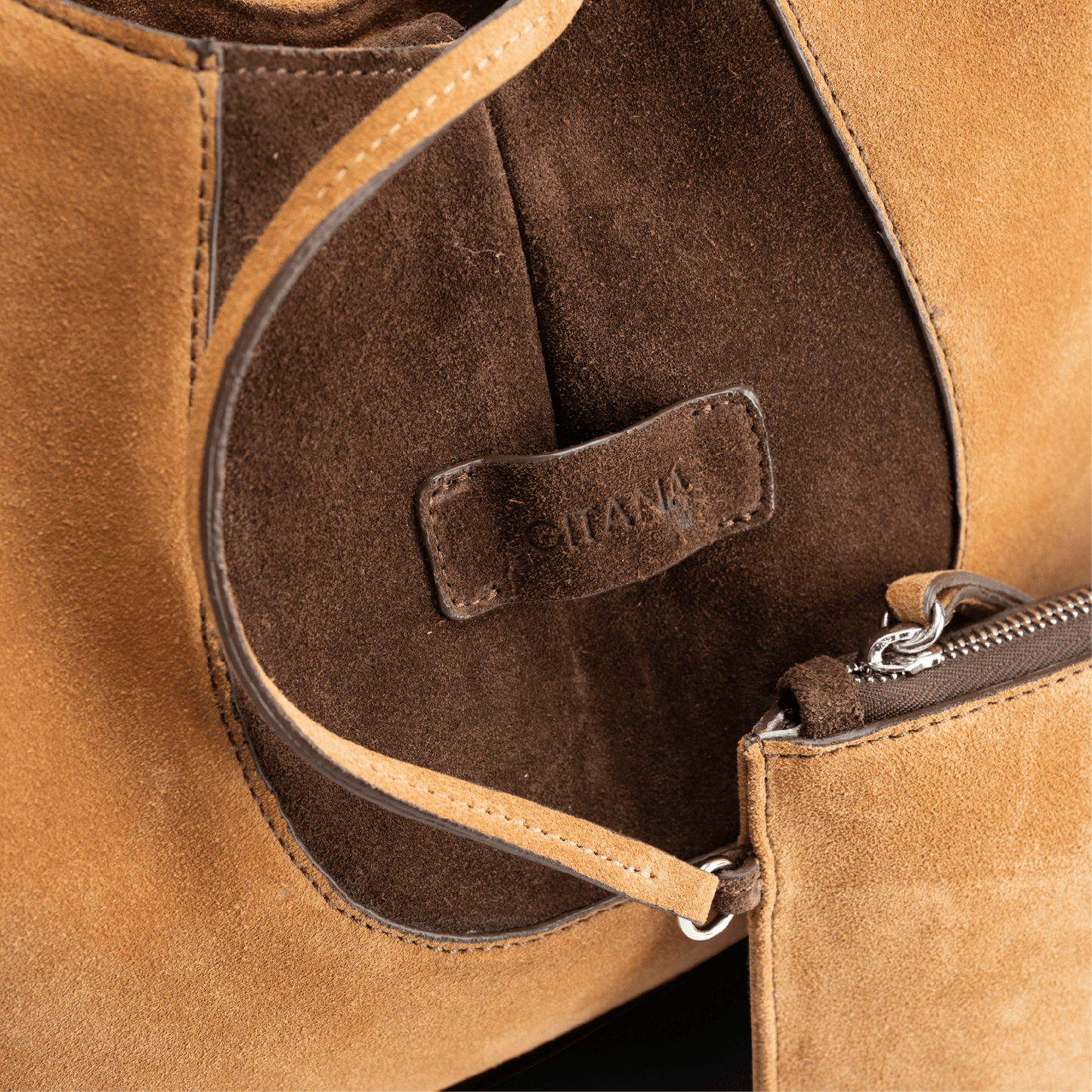 Close-up view of a caramel and chocolate luxury suede tote bag with a matching small pouch attached by a strap, displayed on a white background.