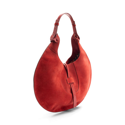 The side view of a scarlet luxury designer suede tote bag, showcasing the curved designer silhouette against a white background.