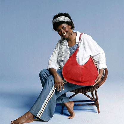 Woman sitting on a chair holding a red bag against a light blue background