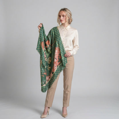 A woman wearing a cream silk blouse, beige tailored trousers and an emerald green square scarf.