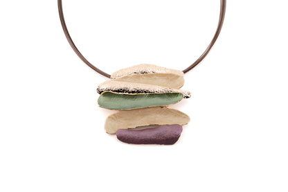 Statement necklace with layered organic bar pendant in cream, sage green and mauve with gold metallic edges, suspended from brown steel multi-cable on white background