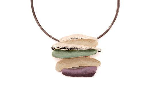 Statement necklace with layered organic bar pendant in cream, sage green and mauve with gold metallic edges, suspended from brown steel multi-cable on white background