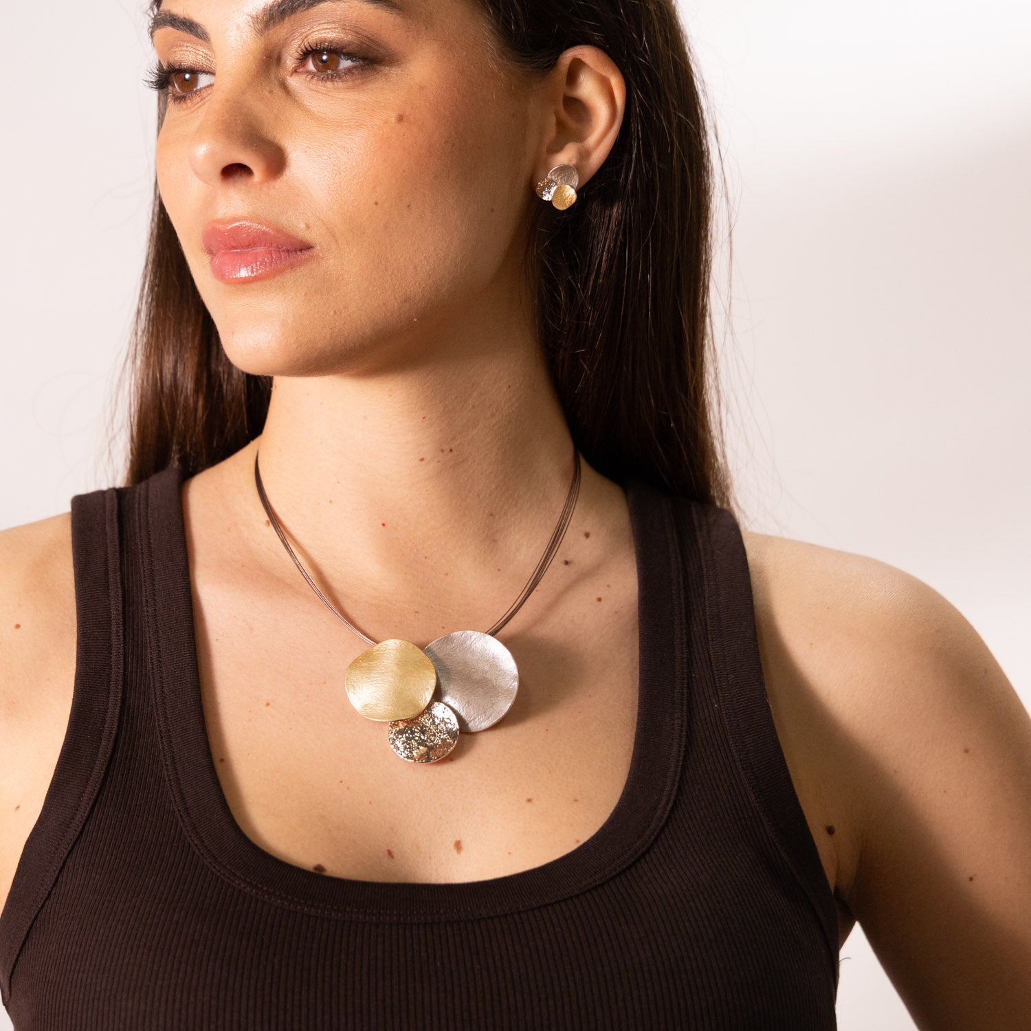 Model wearing short Zamak necklace with three round pendants in rose gold, taupe and champagne enamel