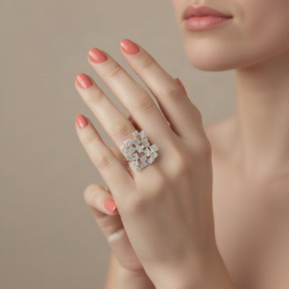 A silver textured geometric ring with a faceted, angular design, worn on a manicured hand.