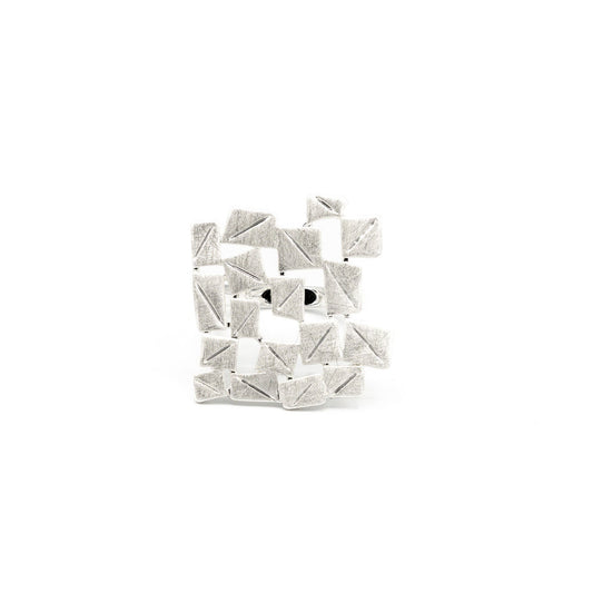 A silver plated zamak ring with juxtaposed small elaborate squares against a white background.