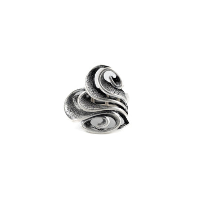 A silver-toned ring with a sculpted, layered design resembling overlapping stylized leaves or petals, shown on a plain white background.