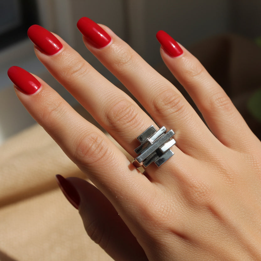 A beautifully manicured hand wearing a silver brick stack ring.