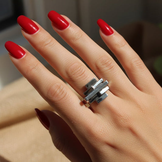 A beautifully manicured hand wearing a silver brick stack ring.