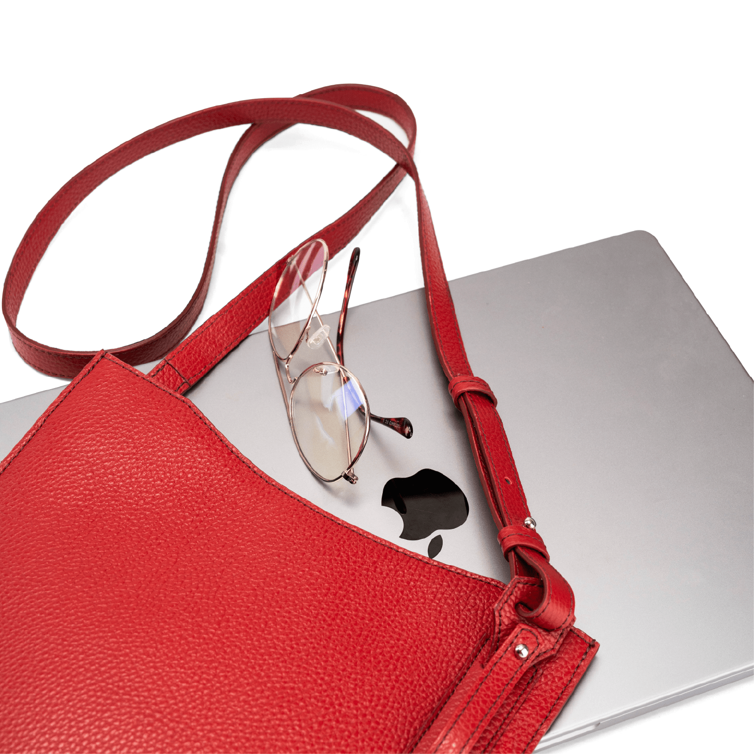 Red calf leather crossbody handbag displayed with MacBook and glasses on a white table to show bag capacity and lifestyle use.