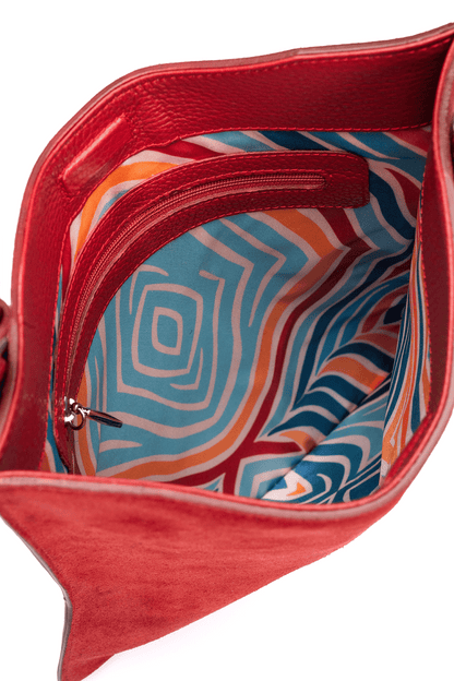Red crossbody suede leather handbag with a colorful interior linning with a geometric pattern on a white background