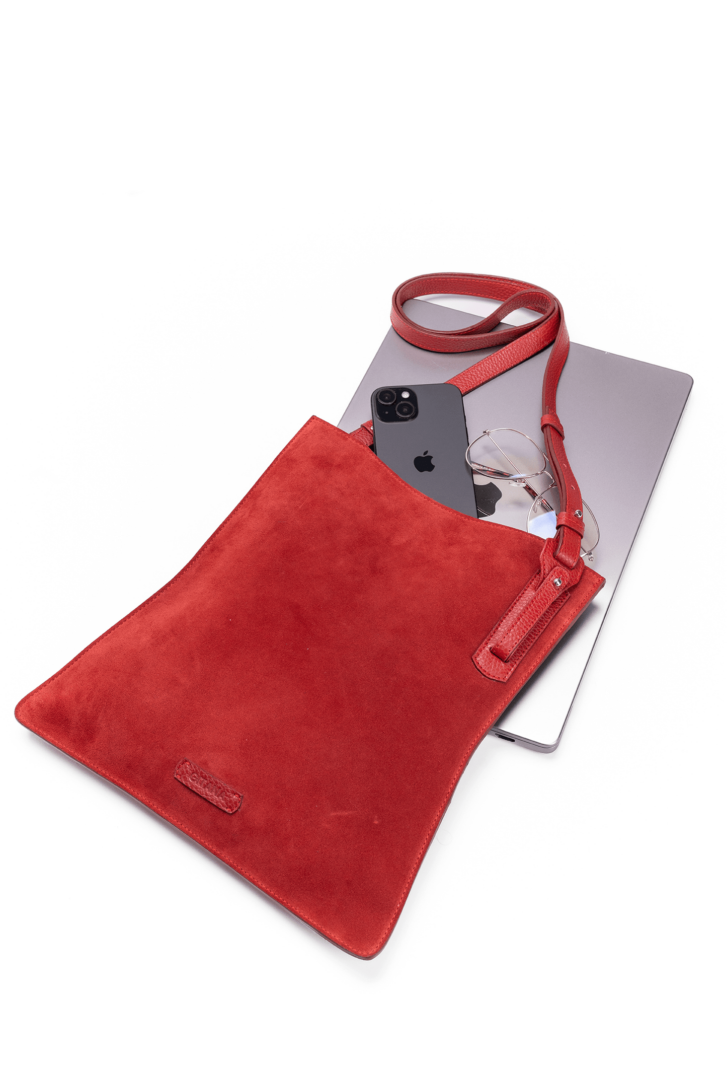 Red suede leather crossbody handbag displayed with Ipad and glasses on a white table to show bag capacity and lifestyle use.