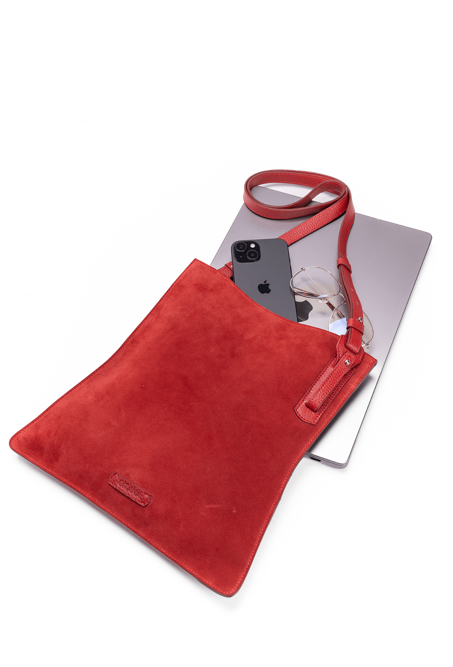 Red suede leather crossbody handbag displayed with Ipad and glasses on a white table to show bag capacity and lifestyle use.