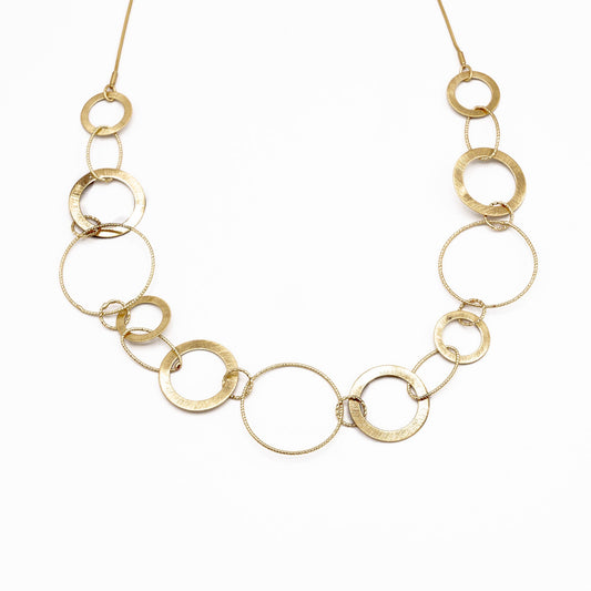 A gold-toned link necklace featuring a series of interlocking open circular rings of varying sizes, displayed against a clean white background.