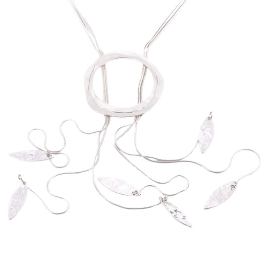A silver plated necklace with several strands of snake chain with hammered leaves at the strand ends set on a white background.