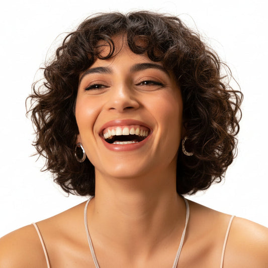 A woman with brown hair is shown in a close-up portrait wearing a silver-toned double-ring hoop earring against a plain white background.